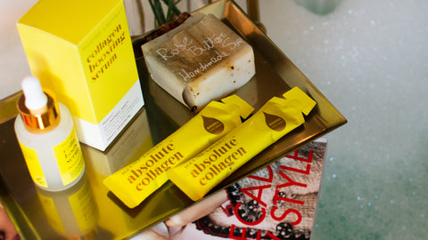 Photo showing a bottle of Maxerum and some Absolute Collagen sachets on a decorative tray with a bubble bath in the background