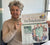 Photo showing a white woman with short silver hair smiling and holding up a copy of The Daily Telegraph, which has a photo of her on the page
