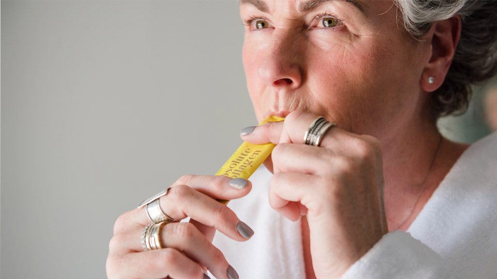 Photo of Maxine Laceby wearing a white dressing gown and taking an Absolute Collagen sachet