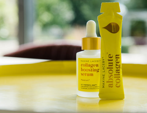 Photo of a yellow Absolute Collagen sachet standing alongside a yellow Absolute Collagen serum bottle on a green and yellow blurred background