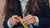 Photo of a woman with long wavy brown hair, she is holding a yellow Absolute Collagen sachet in her hands
