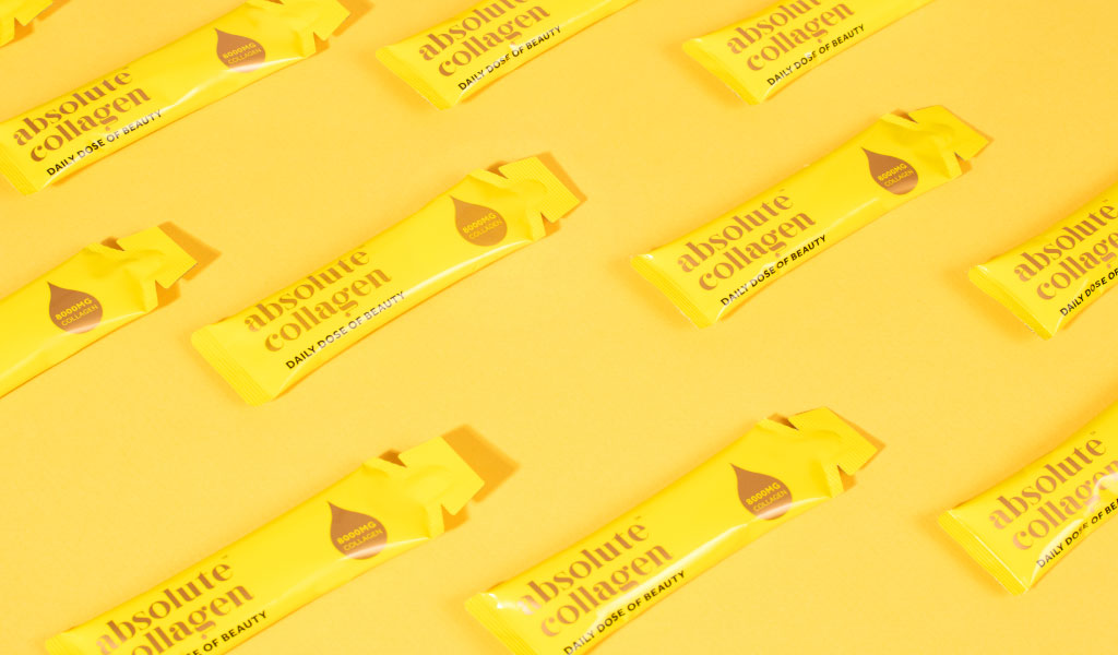 Several yellow Absolute Collagen sachets on a yellow background