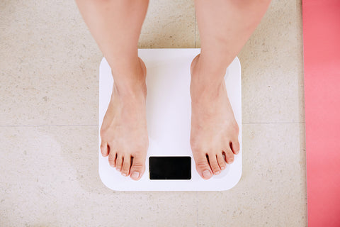photo of a white woman's feet on bathroom scales as she weighs herself